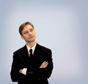 Young business in black suit looking upwards and thinking