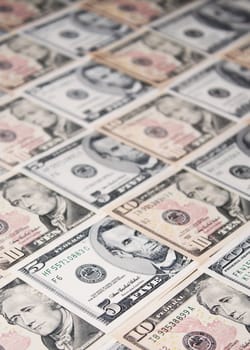 Background of five, ten and a hundred dollar banknotes neatly arranged, with shallow depth of field.