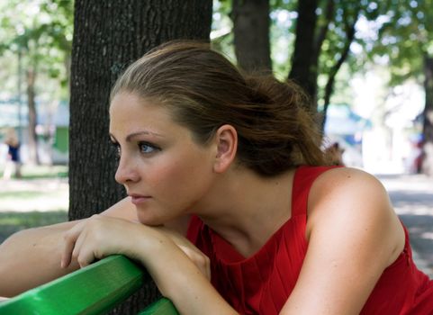 sad girl sitting on a bench in the park