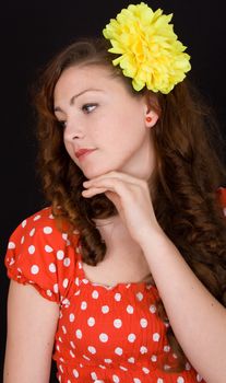 Portrait of a beautiful girl with a flower in her hair on a black background