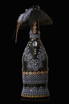 Bottle of champagne draped with leather and lace isolated over black background