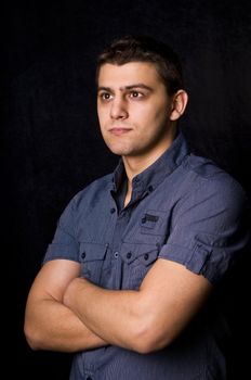 Serious casual young man in jeans on black background