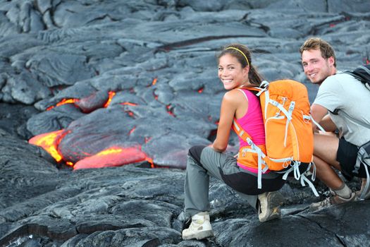 Hawaii lava tourist on hike. Tourists hiking near flowing lava from Kilauea volcano around Hawaii volcanoes national park, USA. Multiethnic couple.