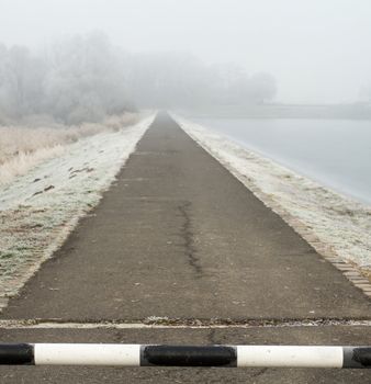 road to far away with barrier on freeze hoarfrosted landscape