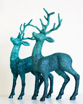A pair of green glittery Christmas reindeer statues, isolated on white