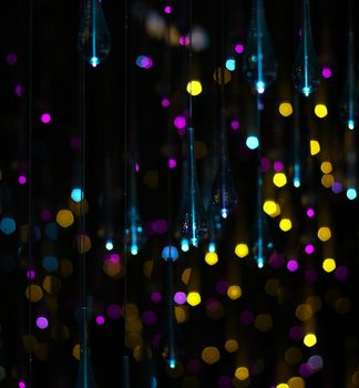 hanging glass drops with Pink, yellow, blue glitter bokeh on black background