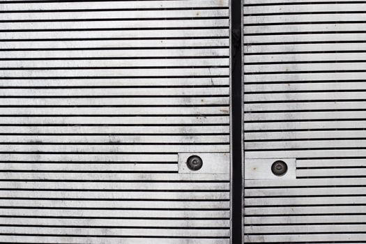 Close up of panels with horizontal slats cladding a facade with rusty screws