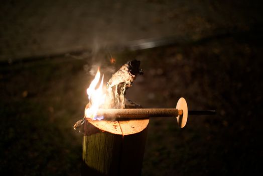 Torch burning on a wooden stump at night
