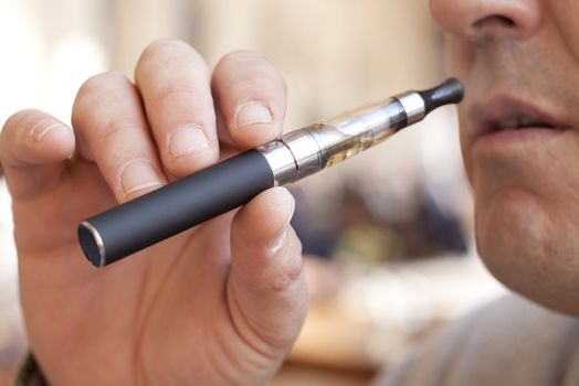 Close up of a man inhaling from an electronic cigarette