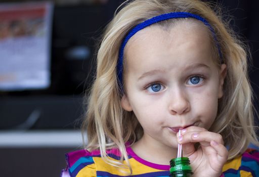 A young child drinking from a bottle with a straw