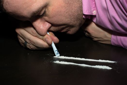 Drug Abuse: Young man sniffing cocaine using a EURO note