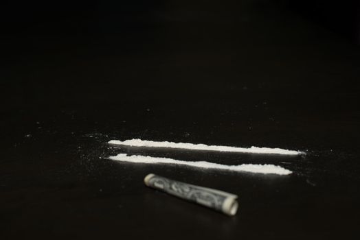 Drug abuse: Two rows of cocaine being prepared for sniffing with a dollar bill lying in the front