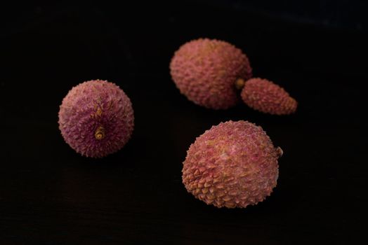 Exotic lychee (litchi) fruit on dark wooden table background