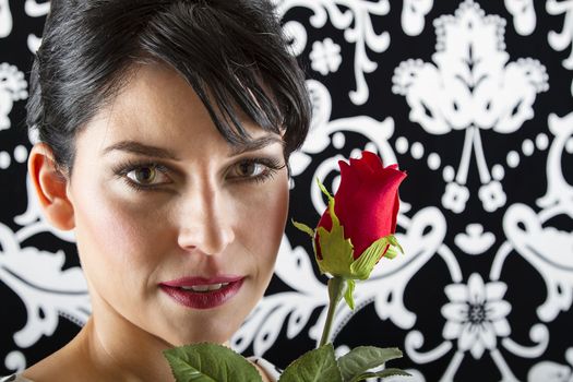 young woman in front of a black and white textured, holding a rose