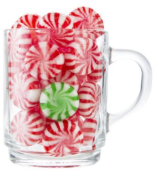 hard red and white candy mints with a green one in the middke in a transparent cup