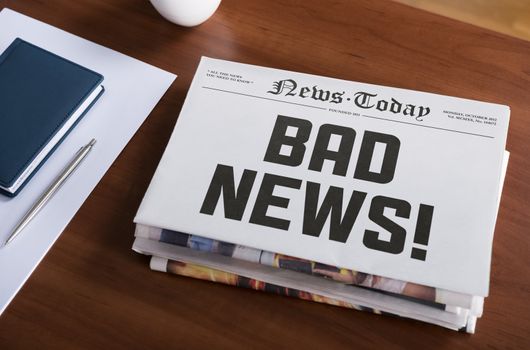 Newspaper concept with hot topic "Bad news" lying on office desk.
