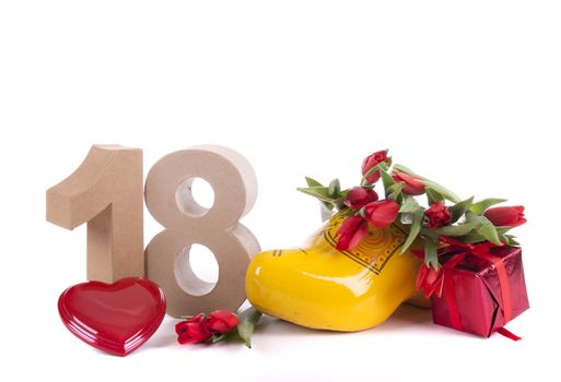 Number of age in a colorful studio setting and Dutch looking attributes like a clog woonden shoe and tulips