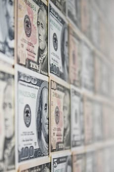 Background of ten and a hundred dollar banknotes on a wall, with shallow depth of field.