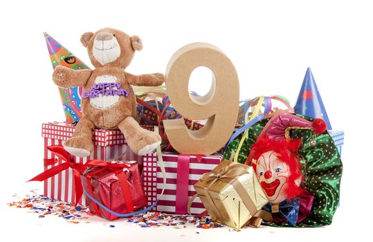 Number of age in a colorful studio setting with paper party hats, a red heart and gifts on a bottom of confetti for  childrens birthday party

