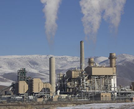 Power Plant smokestacks with blue skies and mountains