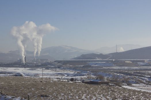 Power Plant smokestacks with blue skies and mountains