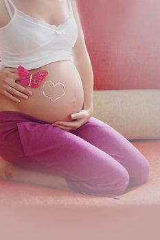 Pregnant woman belly with drawn love sign