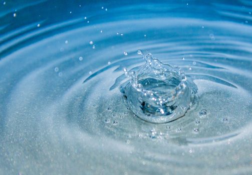 Water splash with small drops in blue background