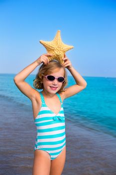 child kid girl in summer beach vacations with starfish and aqua sea