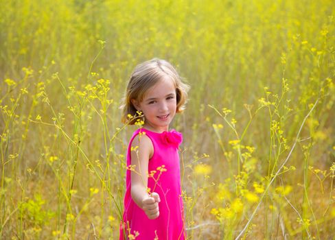 child kid girl in spring yellow flowers field and pink dress in Mediterranean forest