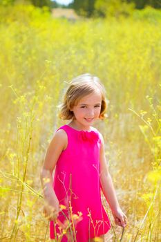 child kid girl in spring yellow flowers field and pink dress in Mediterranean forest