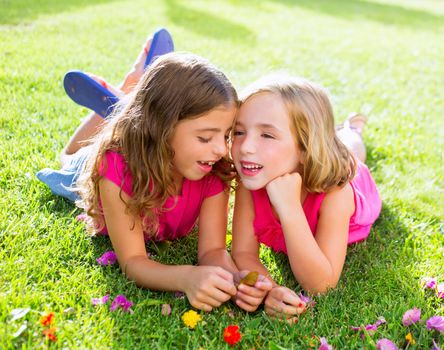 children friend girls playing whispering on flowers grass in vacations