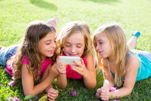 children friend girls group playing internet with mobile smartphone on grass