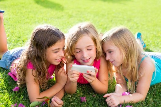 children friend girls group playing internet with mobile smartphone on grass