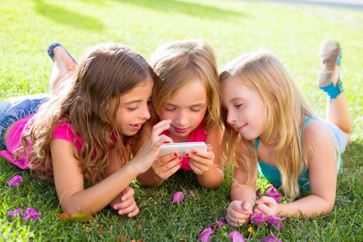 children friend girls group playing internet with mobile smartphone on grass