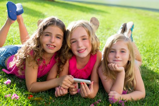 children friend girls group playing internet with mobile smartphone on grass