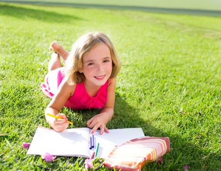 child kid girl doing homework smiling happy lying on grass garden with flowers