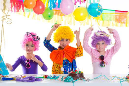 Children happy birthday party with clown wigs and chocolate cake