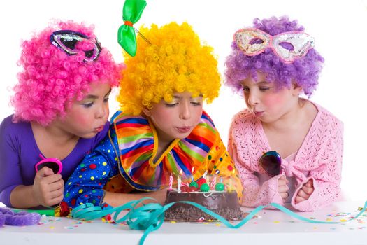 Children happy birthday party with clown wigs blowing chocolate cake candles