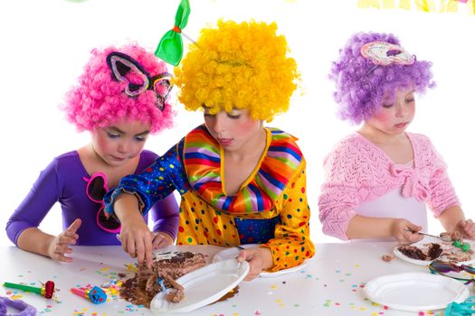 Children happy birthday party eating chocolate cake with clown wigs