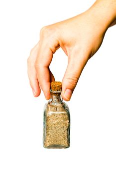 Pretty female hand show a small glass bottle with beach sand in it is interior
