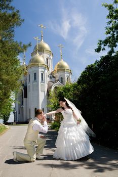 groom kisses hand of bride near the chirch