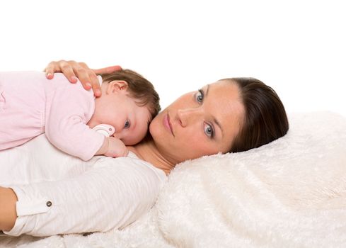 Baby girl and mother lying together on white fur almost sleeping with pacifier