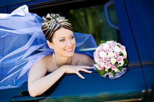 happy bride with flower bouquet siting in the car