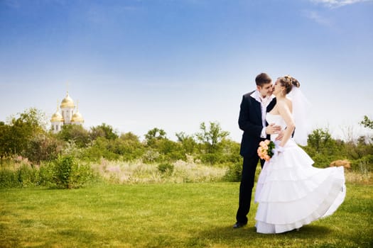 groom kisses bride near the church