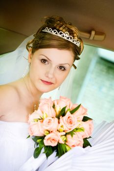 happy bride with flower bouquet siting in the car