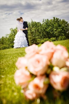groom kisses bride and a flower bouquet near by