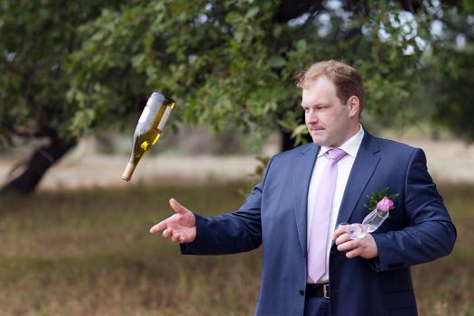 well-dressed young smart man playing with the bottle