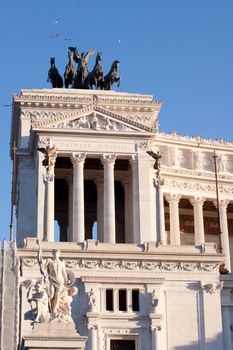 A dark equestrian statue in fron of white official building in Roma
