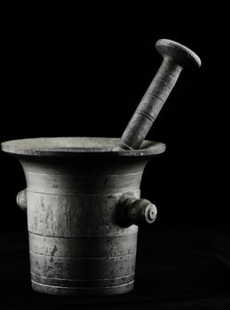 Old mortar with pestle on black backround