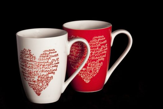 2 coffeecups with hearts on a black background